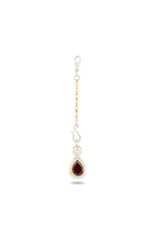 Introducing the “My Blood, Your Blood, Our Blood Charm” by Jessica de Lotz Jewellery—a single earring that features interwoven gold and silver chains, a decorative silver hook, and a teardrop-shaped red gemstone set in polished silver. Inspired by sisterhood jewelry from the Practical Magic charms collection, this standout piece is showcased against a plain white background, drawing attention to its intricate craftsmanship and striking colors.