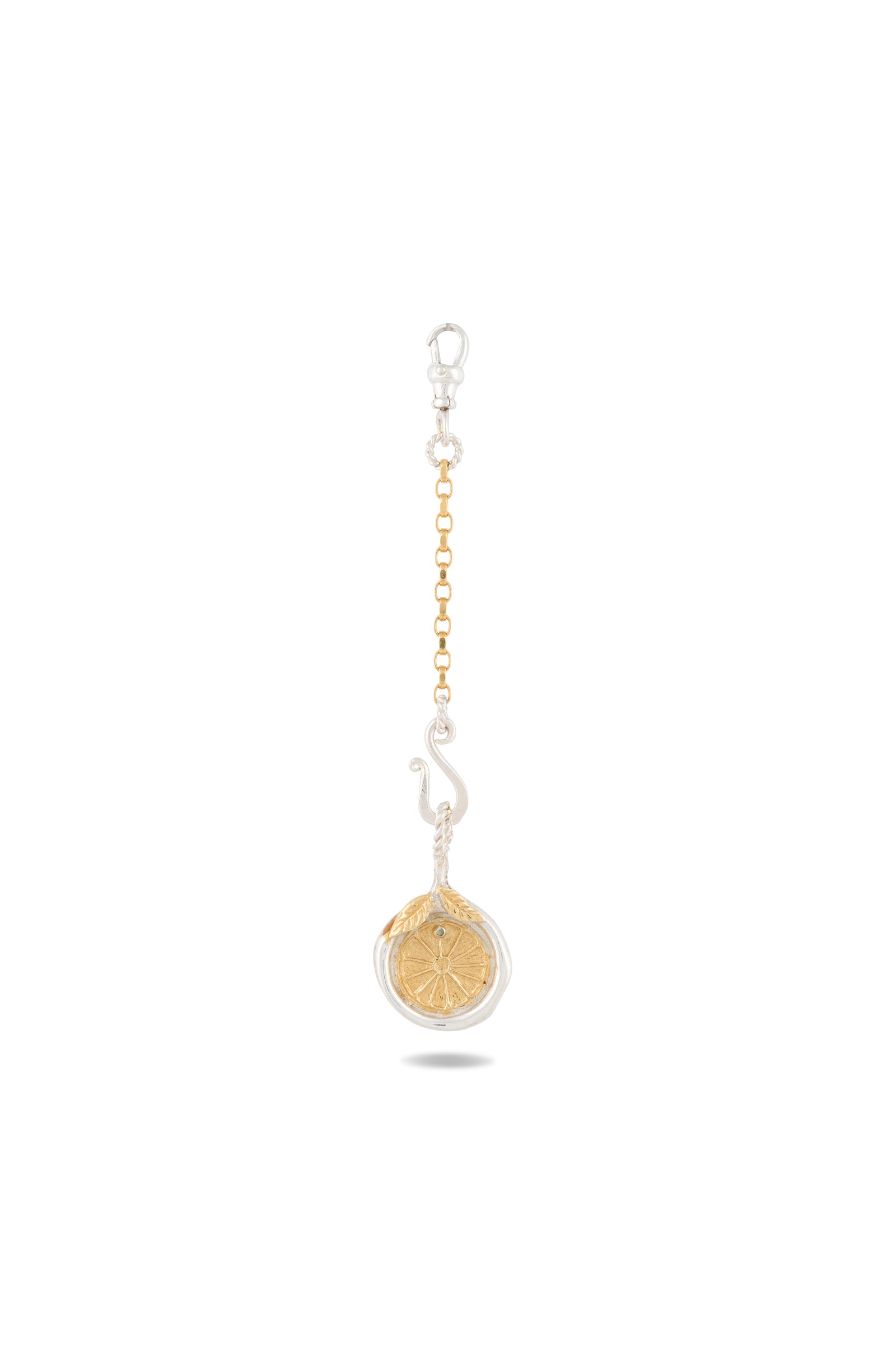 The Midnight Margarita Lime Charm by Jessica de Lotz Jewellery features a round, vibrant green dried lime slice encased in a clear circular frame, suspended from a gold chain with a silver lobster clasp and adorned with a decorative silver swirl. Reminiscent of Practical Magic charms and ideal for modern-day chatelaines, this unique accessory adds a touch of kitchen witchcraft to your everyday essentials. The background is plain white.