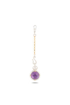 A gold and silver chain with a lobster clasp displays the ’There’s A Little Witch In All Of Us’ Charm by Jessica de Lotz Jewellery—a round amethyst cabochon set in silver. The pendant, echoing the style of a modern-day chatelaine, features metallic accents and is photographed against a white background to highlight the stone’s polished surface and vibrant hue.
