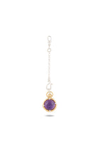 A silver chain pendant from Jessica de Lotz Jewellery, titled “There’s A Little Witch In All Of Us” Charm, features a round amethyst cabochon set in a gold bezel at the end and fastens with a lobster clasp. Inspired by modern-day chatelaine designs, this elegant piece is displayed against a plain white background, with the shadow of the pendant visible beneath it.