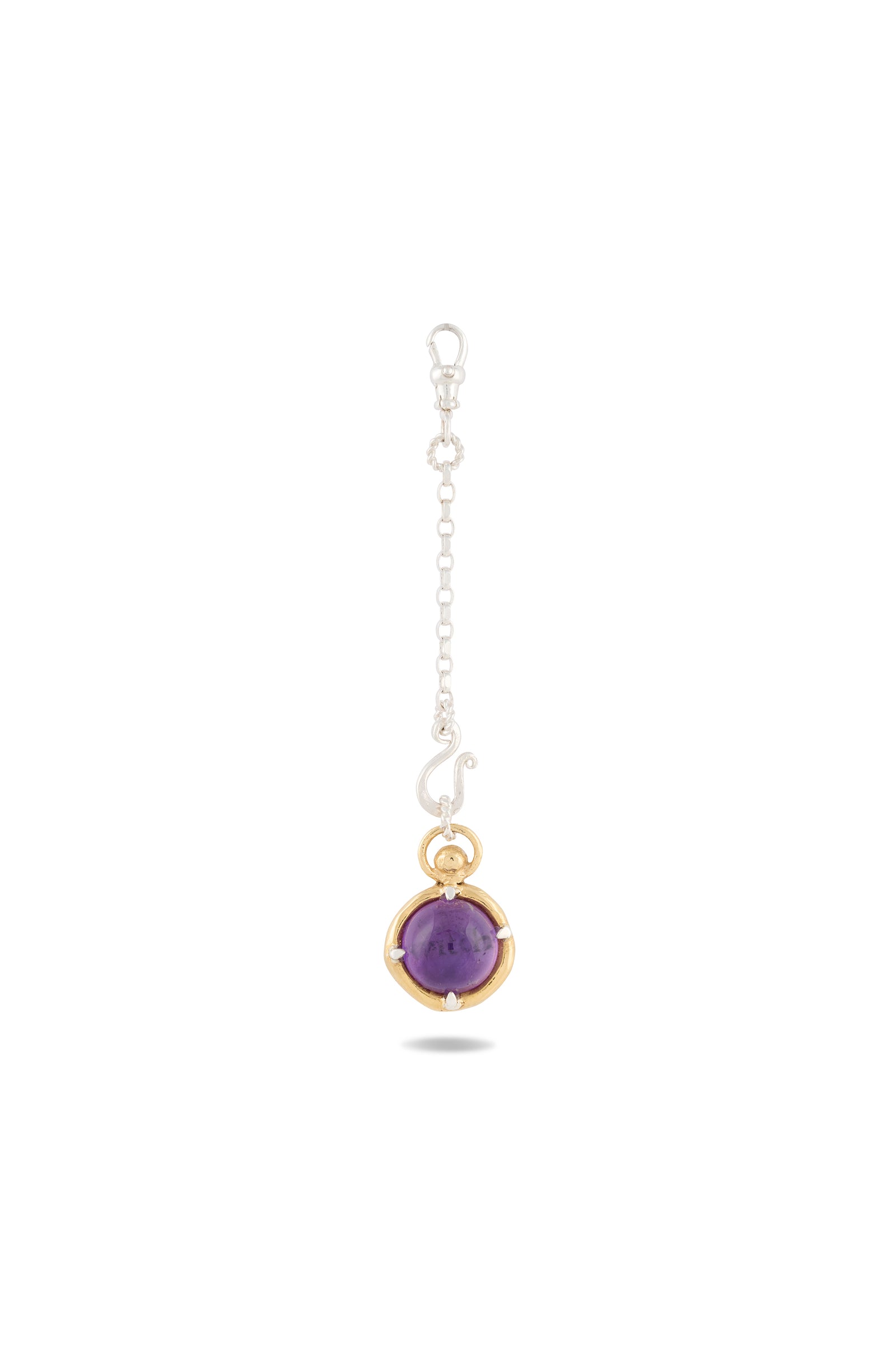 A silver chain pendant from Jessica de Lotz Jewellery, titled “There’s A Little Witch In All Of Us” Charm, features a round amethyst cabochon set in a gold bezel at the end and fastens with a lobster clasp. Inspired by modern-day chatelaine designs, this elegant piece is displayed against a plain white background, with the shadow of the pendant visible beneath it.