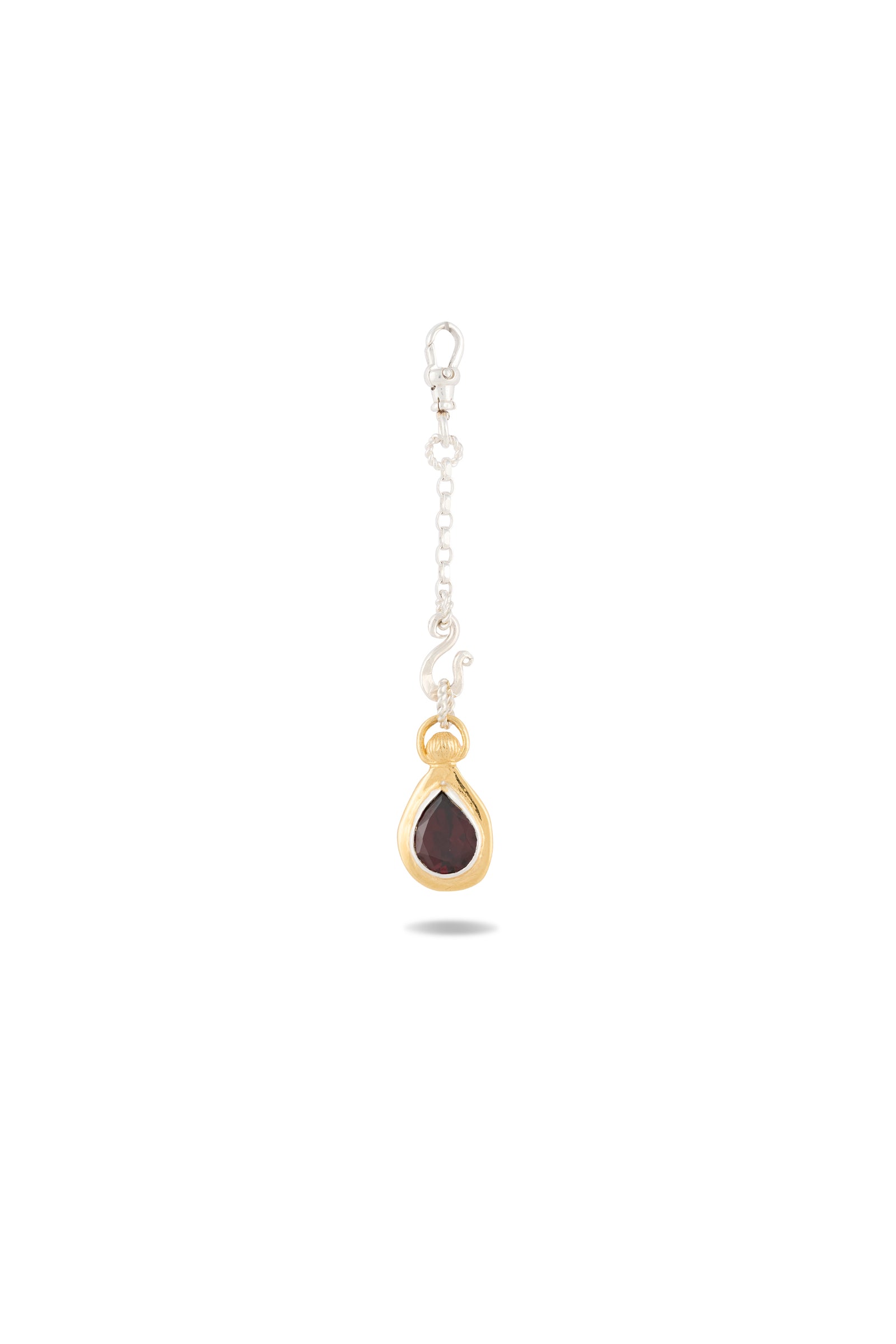 The “My Blood, Your Blood, Our Blood Charm” by Jessica de Lotz Jewellery features a single silver chain earring with a gold-framed, teardrop-shaped dark gemstone pendant and a sleek silver clasp. Shown against a plain white background, this striking piece of sisterhood jewelry is inspired by the magical charms of Practical Magic.