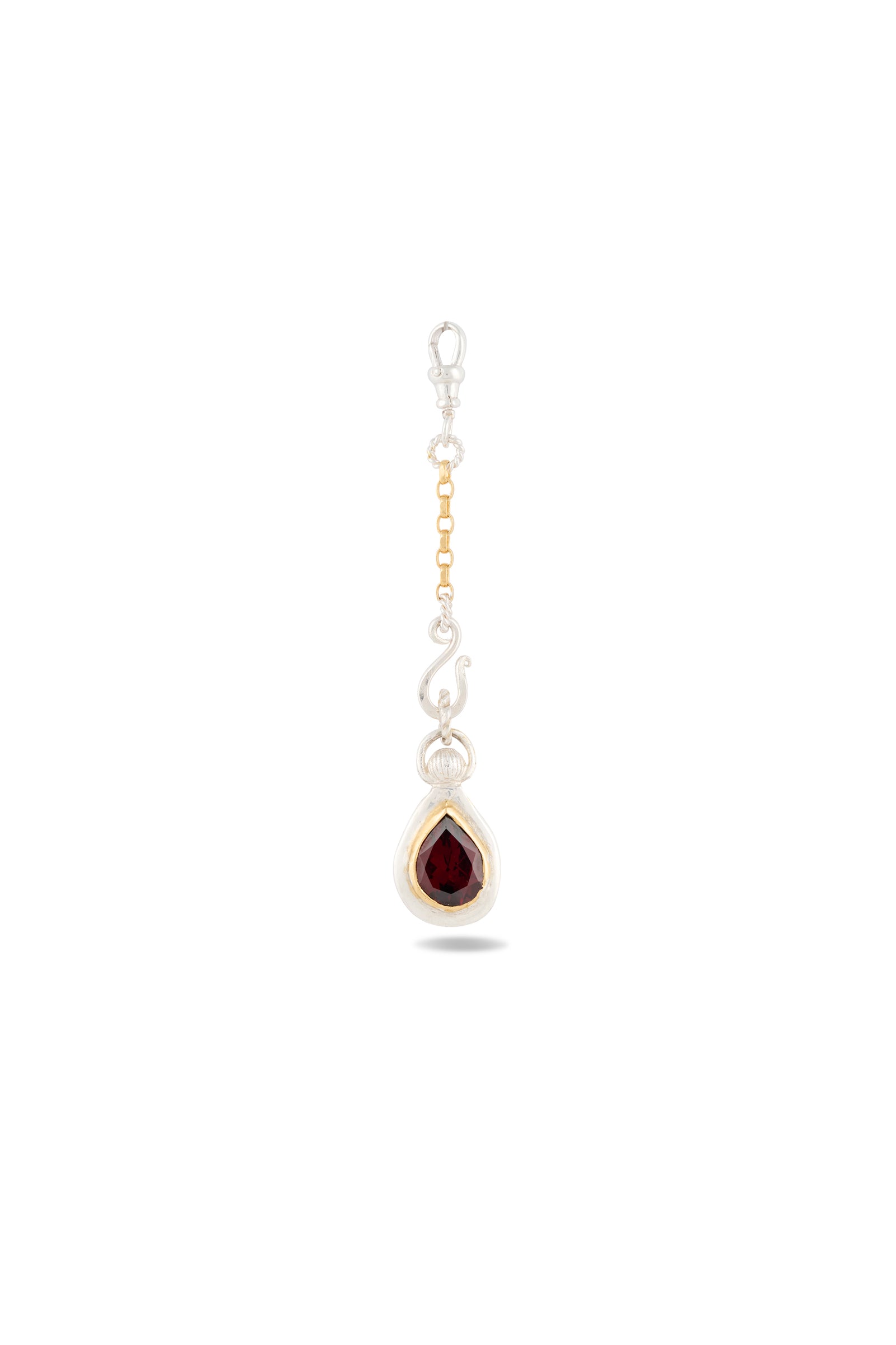 Introducing “My Blood, Your Blood, Our Blood Charm” by Jessica de Lotz Jewellery—a single earring featuring a gold and silver chain adorned with a teardrop-shaped dark red gemstone set in an elegant silver and gold bezel. Displayed against a plain white background, this striking piece of sisterhood jewelry evokes the magical essence of charms from Practical Magic.