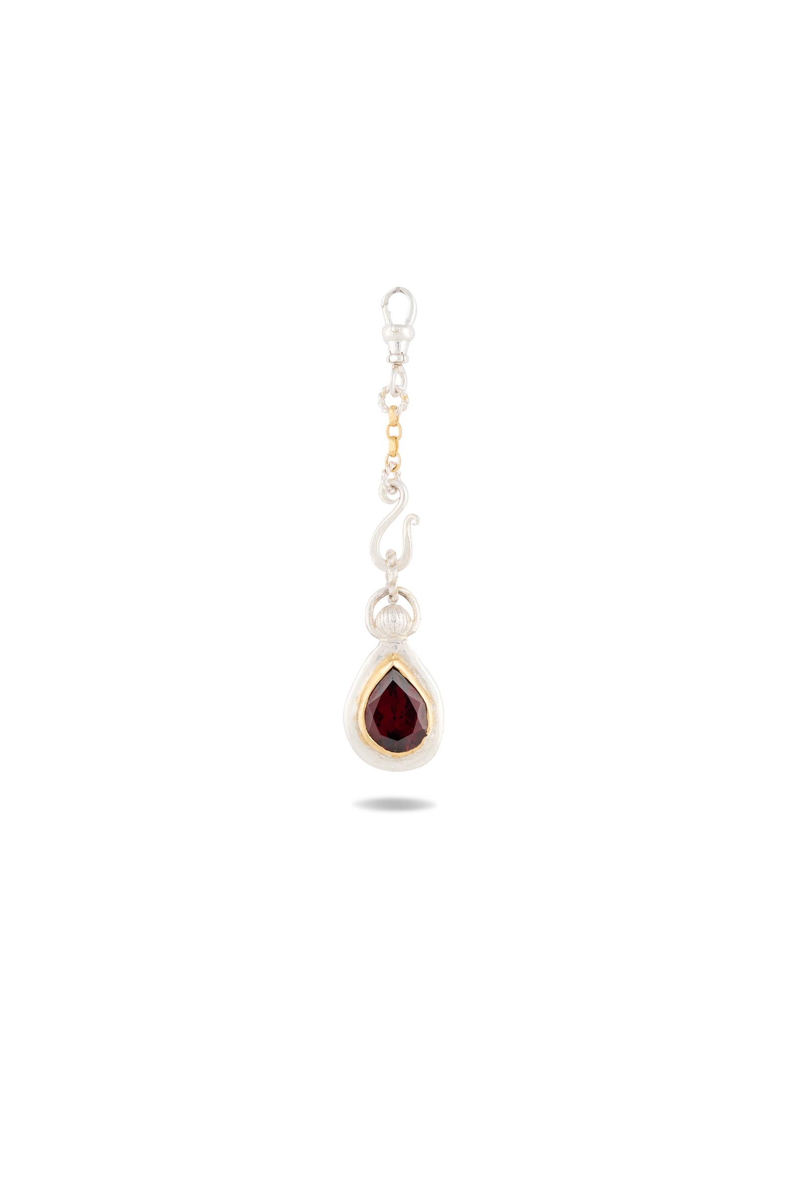 Introducing the My Blood, Your Blood, Our Blood Charm by Jessica de Lotz Jewellery: This delicate silver earring showcases a teardrop-shaped red gemstone set in a simple bezel, evoking the mystique of Practical Magic charms. A curving hook and a small gold bead accent above the gem recall the warmth of treasured sisterhood jewelry. The earring is elegantly photographed against a plain white background.