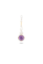 The ’There’s A Little Witch In All Of Us’ Charm by Jessica de Lotz Jewellery is a silver keychain showcasing a large amethyst cabochon encased in a round silver frame with gold accents, reminiscent of Practical Magic charms. The elegant frame connects to a decorative silver hook and chain, evoking the grace of a modern-day chatelaine. The piece is displayed against a plain white background with a soft shadow beneath.
