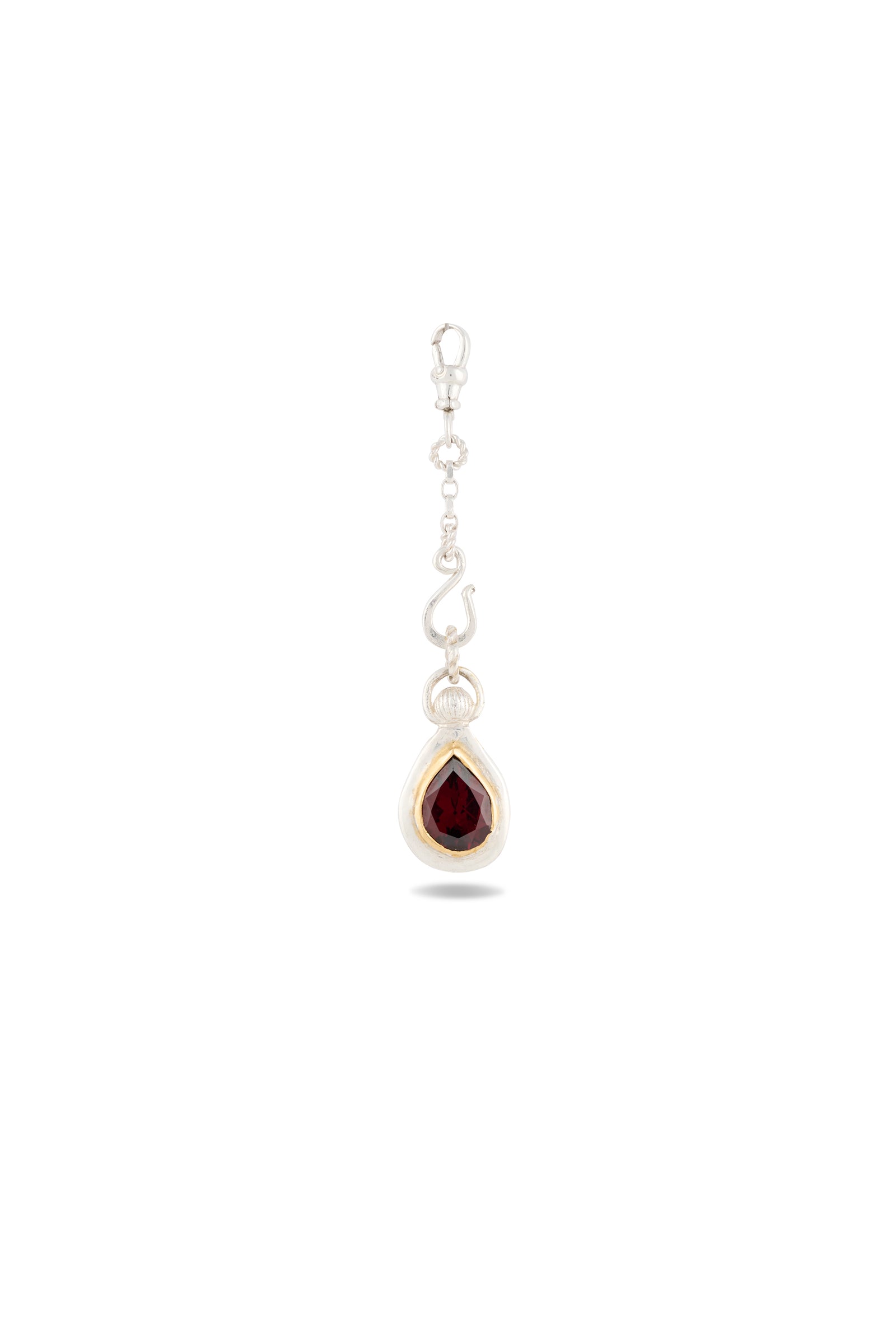 Introducing the My Blood, Your Blood, Our Blood Charm by Jessica de Lotz Jewellery: a striking silver earring featuring a dangling teardrop-shaped deep red gemstone nestled in a silver setting. The decorative hook and chain are adorned with delicate silver accents, evoking the essence of sisterhood and Practical Magic-inspired charms. This unique piece stands out beautifully against the plain white background.