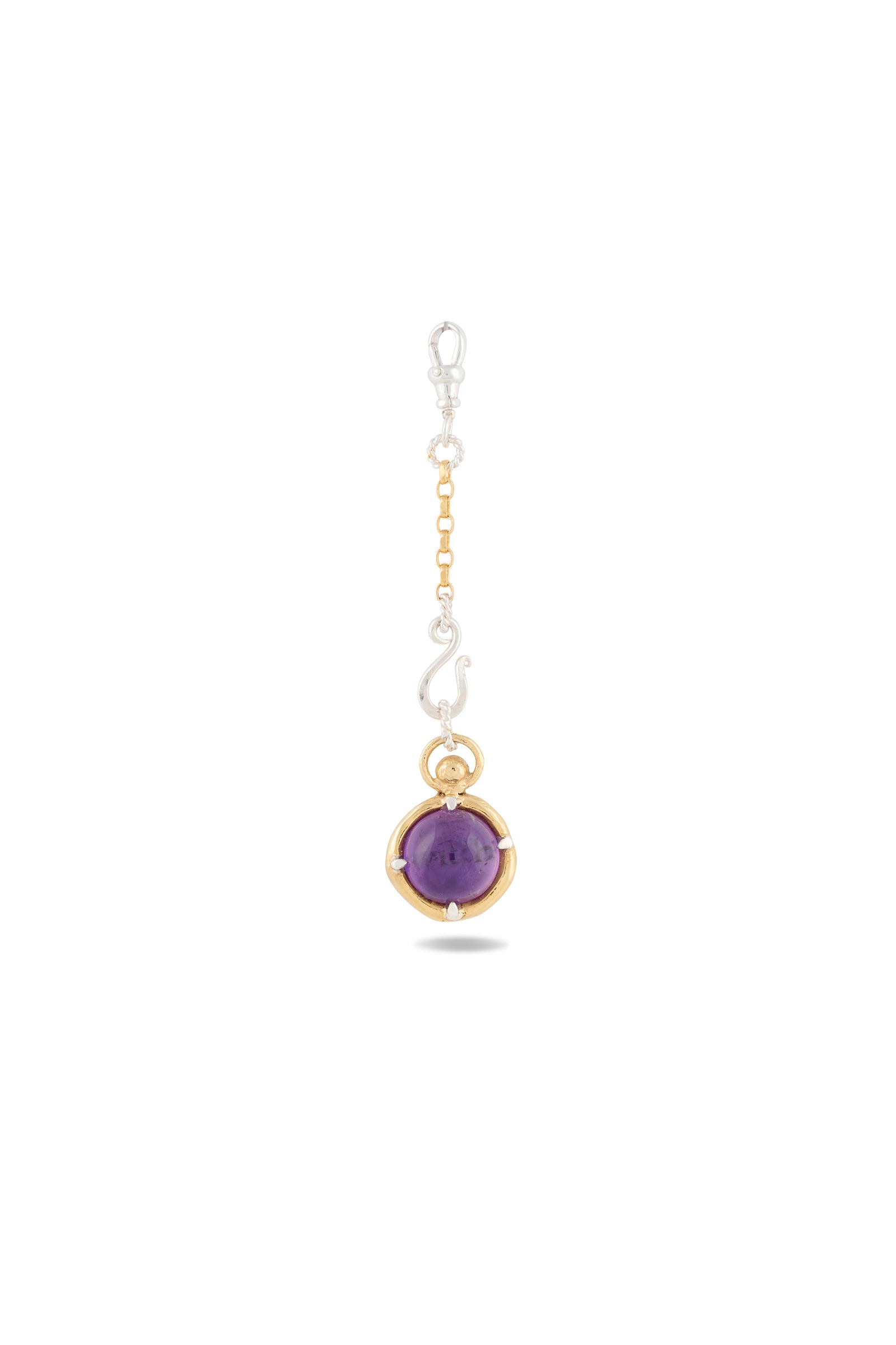 The ’There’s A Little Witch In All Of Us’ Charm by Jessica de Lotz Jewellery features a round amethyst cabochon set in an elegant mix of gold and silver. Suspended from a delicately linked silver and gold chain, this enchanting pendant is showcased against a plain white background. Reminiscent of charms from Practical Magic, it embodies both enchantment and the timeless elegance of a modern-day chatelaine.