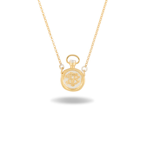 A delicate gold necklace by Jessica de Lotz Jewellery, the Verbenca Botanical Charm Apothecary Top, features a small pendant inspired by a classic apothecary stopper, intricately engraved with ornate initials. Reminiscent of Practical Magic jewelry, the chain is thin and fine, and the pendant casts a soft shadow on a white background.