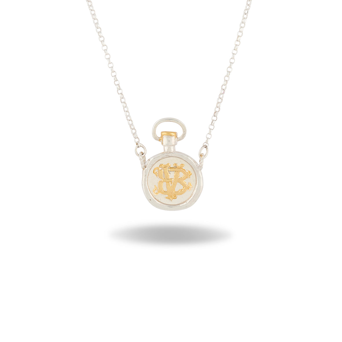 Discover the Verbena Botanical Apothecary Bottle Charm Necklace ~ Limited Edition by Jessica de Lotz Jewellery. This elegant silver necklace features a pendant inspired by vintage apothecary bottles, adorned with an ornate gold monogram at its center. Reminiscent of botanical jewelry, this timeless piece evokes the natural beauty of Verbena Botanical. The charm hangs gracefully from a delicate chain and is showcased against a white background with a soft shadow beneath.