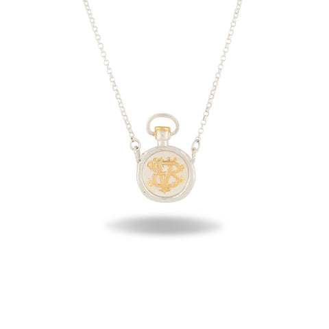 Discover the Verbena Botanical Apothecary Bottle Charm Necklace ~ Limited Edition by Jessica de Lotz Jewellery. This elegant silver necklace features a pendant inspired by vintage apothecary bottles, adorned with an ornate gold monogram at its center. Reminiscent of botanical jewelry, this timeless piece evokes the natural beauty of Verbena Botanical. The charm hangs gracefully from a delicate chain and is showcased against a white background with a soft shadow beneath.