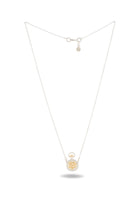 A delicate silver necklace from Jessica de Lotz Jewellery, the Verbena Botanical Apothecary Bottle Charm Necklace ~ Limited Edition, features a small, round pocket-watch pendant with a gold-colored snowflake design at the center. This botanical jewelry piece is clasped at the top, its chain forming a graceful V shape. Near the clasp is a tiny charm inspired by classic wax-seal charm necklaces from Verbena Botanical.