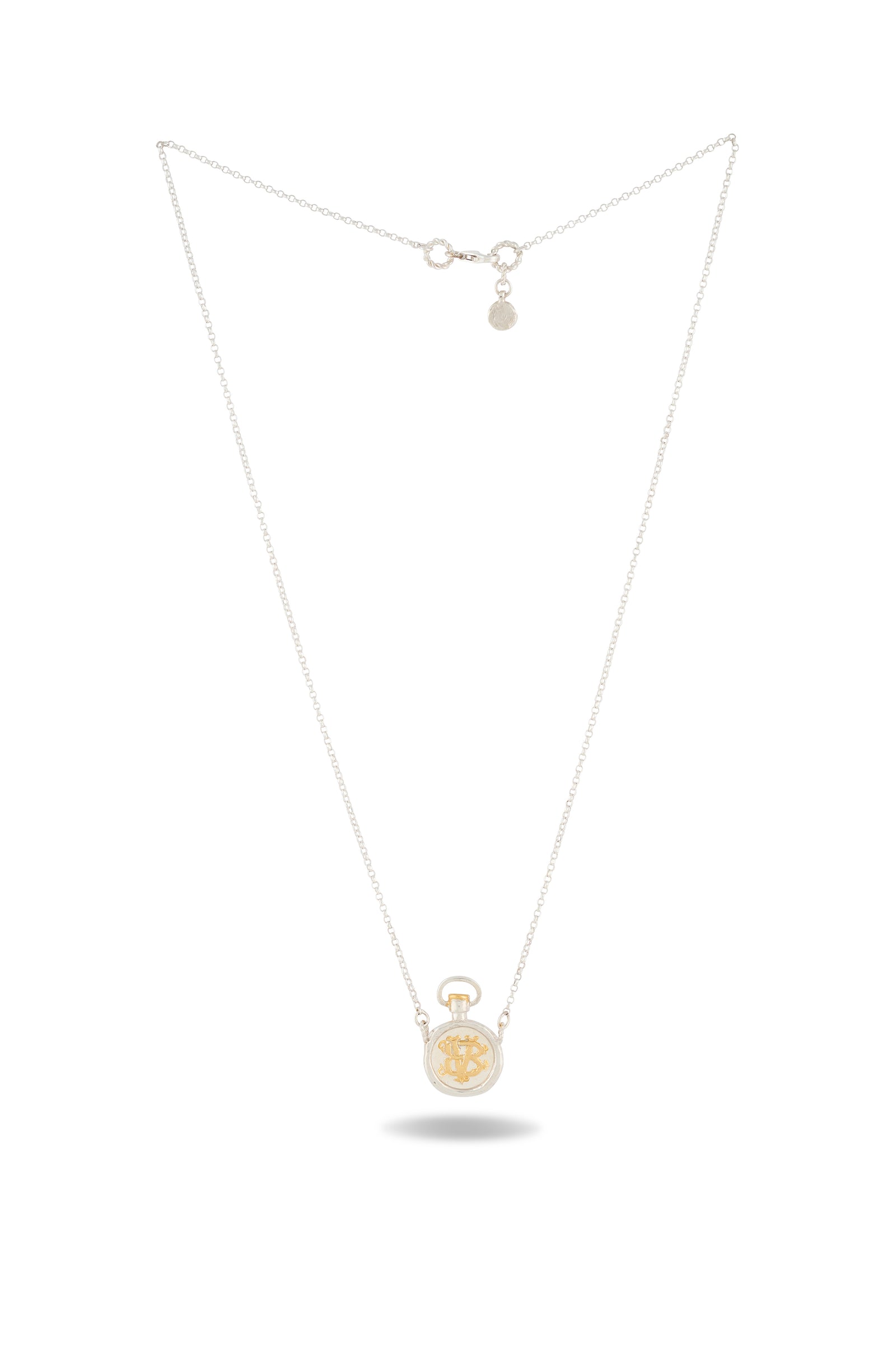 A delicate silver necklace from Jessica de Lotz Jewellery, the Verbena Botanical Apothecary Bottle Charm Necklace ~ Limited Edition, features a small, round pocket-watch pendant with a gold-colored snowflake design at the center. This botanical jewelry piece is clasped at the top, its chain forming a graceful V shape. Near the clasp is a tiny charm inspired by classic wax-seal charm necklaces from Verbena Botanical.