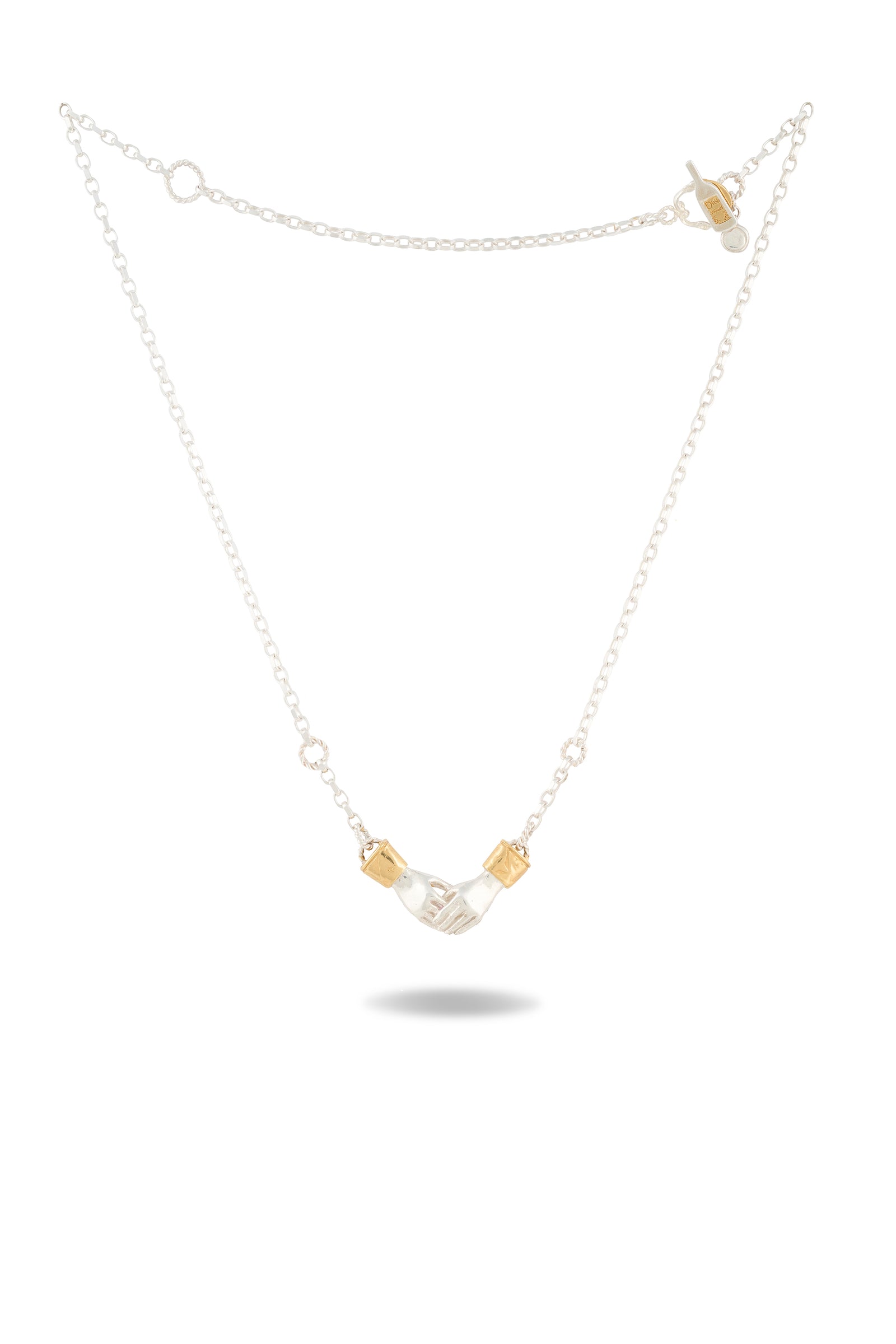 A delicate silver chain necklace, the Chatelaine Hand Necklace by Jessica de Lotz Jewellery, features a small sculpted silver hand charm at its center—reminiscent of classic chatelaine designs—and is flanked by two gold-tone rectangular beads. The beautiful piece is displayed flat on a white background with a soft shadow beneath.