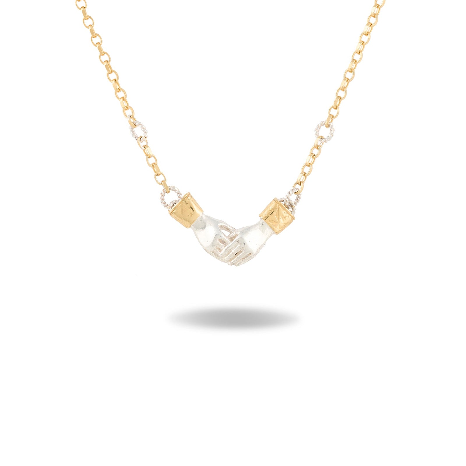 A Practical Magic Chatelaine Hand Necklace by Jessica de Lotz Jewellery, featuring a gold chain with a central pendant shaped like two small hands clasping each other, accented by diamond-like stones on each side. Displayed against a white background with a faint shadow beneath, the design echoes the brand’s iconic style.
