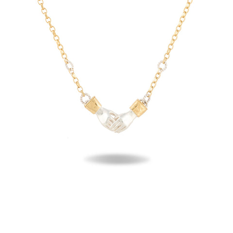 A Practical Magic Chatelaine Hand Necklace by Jessica de Lotz Jewellery, featuring a gold chain with a central pendant shaped like two small hands clasping each other, accented by diamond-like stones on each side. Displayed against a white background with a faint shadow beneath, the design echoes the brand’s iconic style.
