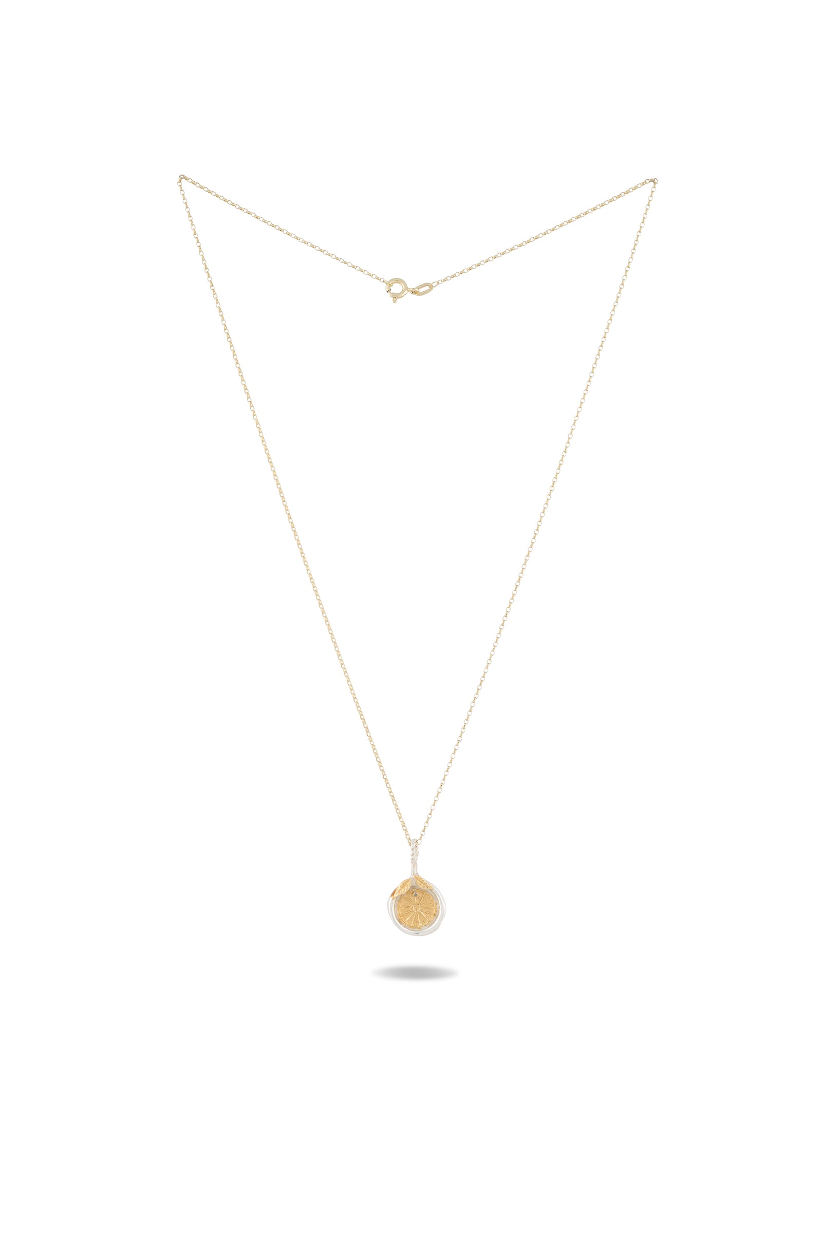 Midnight Margarita Lime Charm necklace by Jessica de Lotz Jewellery, featuring a round, flat pendant engraved with a tree design. Reminiscent of a modern-day chatelaine, this elegant gold chain piece evokes the spirit of Practical Magic charms. The necklace is presented against a plain white background, with the pendant centered and the chain forming a symmetrical V-shape above it.