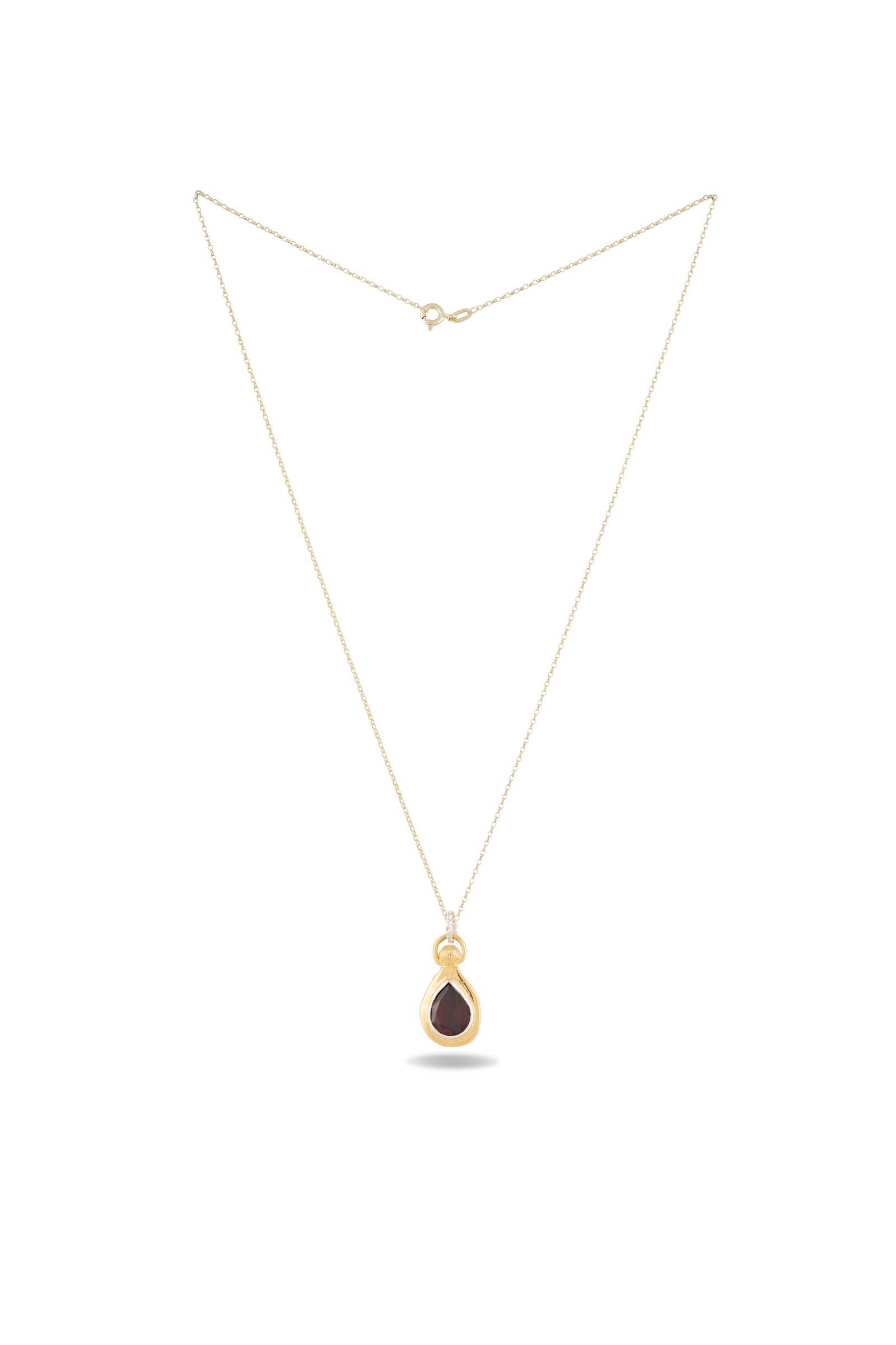 A delicate gold chain necklace from Jessica de Lotz Jewellery showcases the “My Blood, Your Blood, Our Blood Charm,” a small teardrop-shaped pendant with a dark, glossy center encased in gold. Reminiscent of sisterhood jewelry from Practical Magic charms, the necklace is displayed against a plain white background to highlight its simple elegance.