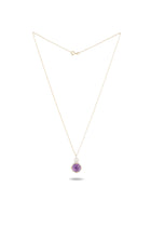 A delicate gold chain necklace featuring the ’There’s A Little Witch In All Of Us’ charm by Jessica de Lotz Jewellery, displayed against a white background. The round amethyst cabochon pendant hangs centrally and casts a faint shadow below, highlighting its simple and elegant design reminiscent of a modern-day chatelaine.