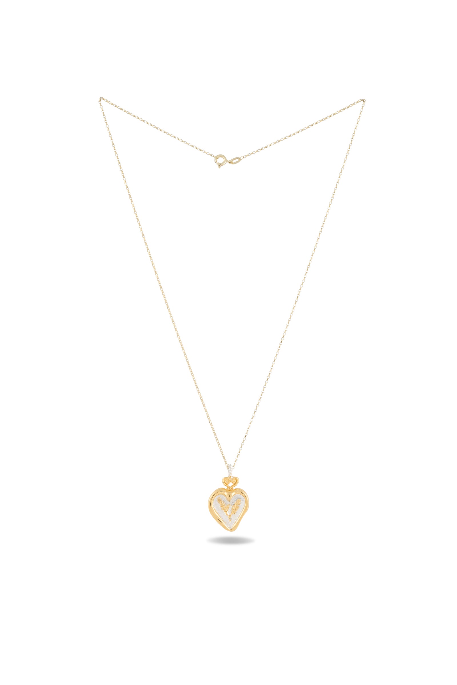The Amas Veritas Spell Charm by Jessica de Lotz Jewellery is a delicate gold necklace with a fine chain, featuring a heart-shaped pendant adorned with a small crown detail—evoking the spirit of sisterhood charms. The piece is displayed on a white background, with a subtle shadow beneath the pendant.