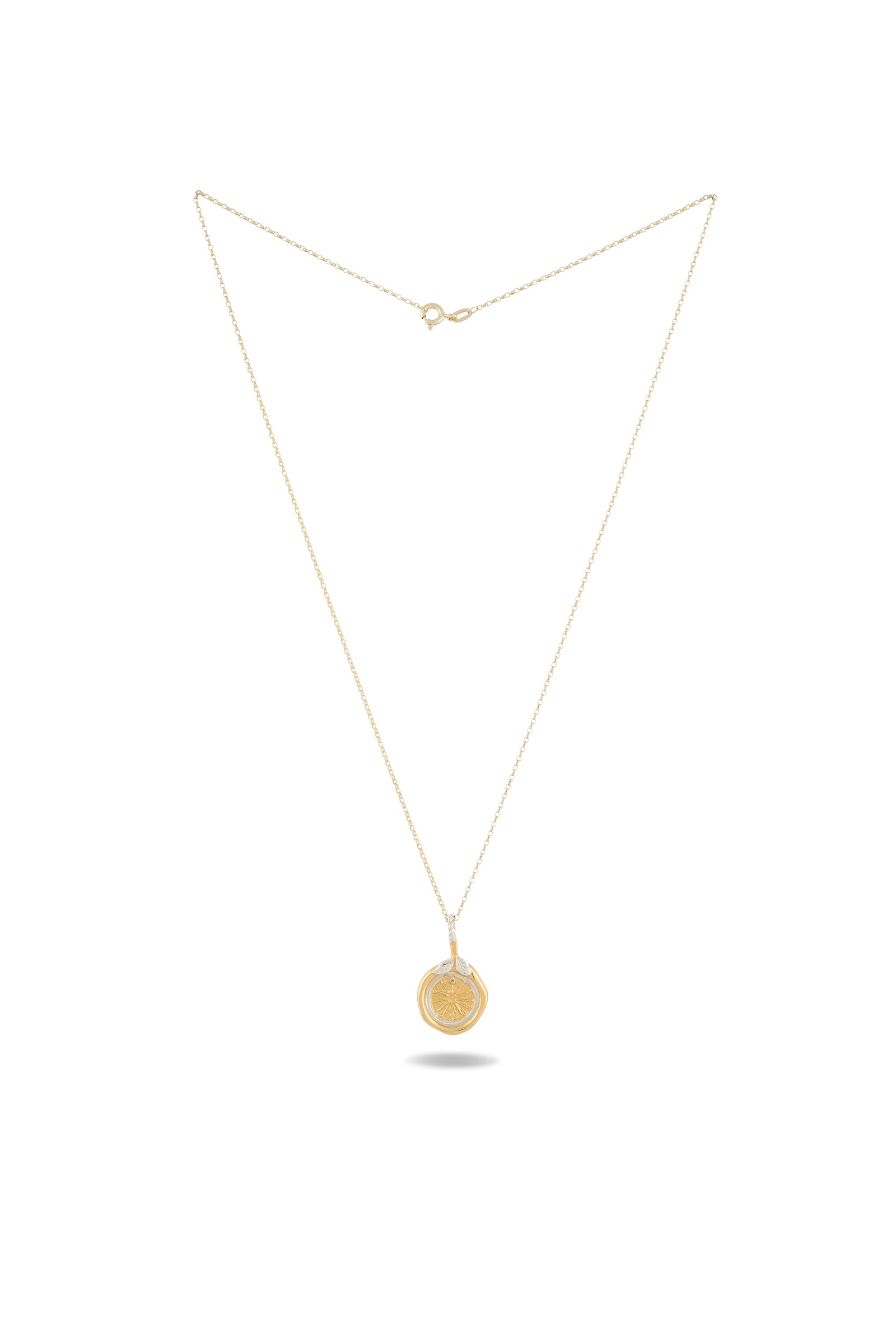 A delicate gold necklace from Jessica de Lotz Jewellery, featuring the Midnight Margarita Lime Charm—a fine chain holds a small round pendant engraved with a design inspired by Practical Magic charms. The necklace is displayed against a plain white background, with a faint shadow beneath the pendant.