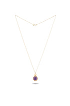 A delicate gold chain necklace by Jessica de Lotz Jewellery features the ’There’s A Little Witch In All Of Us’ charm, a round amethyst cabochon pendant in a gold setting inspired by modern-day chatelaine style, shown against a white background with a small shadow beneath the pendant.