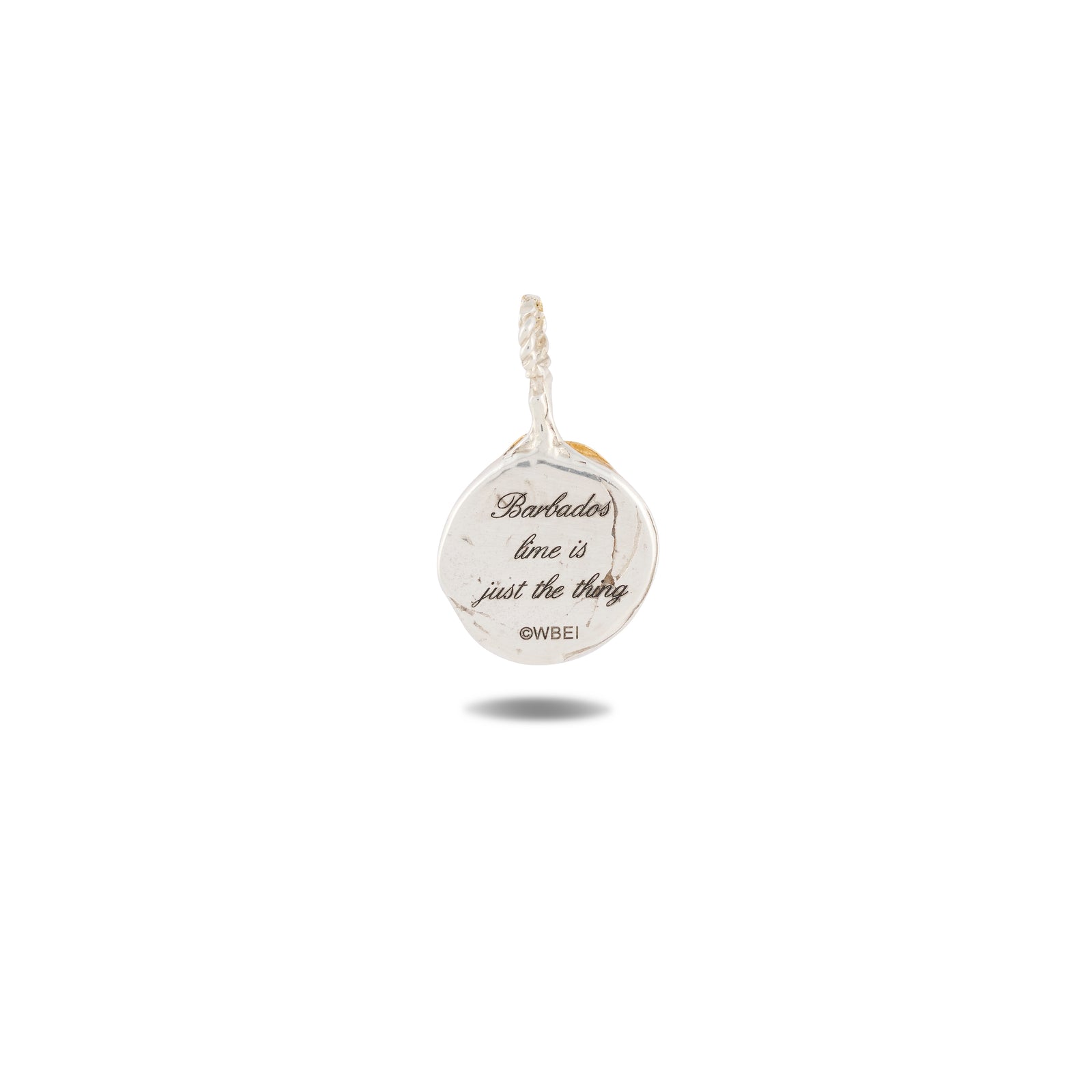 A small silver charm by Jessica de Lotz Jewellery, the Midnight Margarita Charm, is engraved with “Barbados time is just the thing” and “OWBEI” below. Reminiscent of Practical Magic charms, this piece features a loop at the top for easy attachment to a necklace or bracelet and casts a faint shadow on a plain white background.