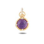 A gold pendant from Jessica de Lotz Jewellery, named “There’s A Little Witch In All Of Us Charm,” showcases a round, polished purple gemstone securely held by four prongs at its center. Inspired by enchanting motifs from *Practical Magic 2*, this charm features a twisted loop for easy attachment to your favorite chain and casts a gentle shadow on a white background. It’s an elegant piece that evokes the timeless allure of wax seal charms and vintage chatelaine hand necklace designs.