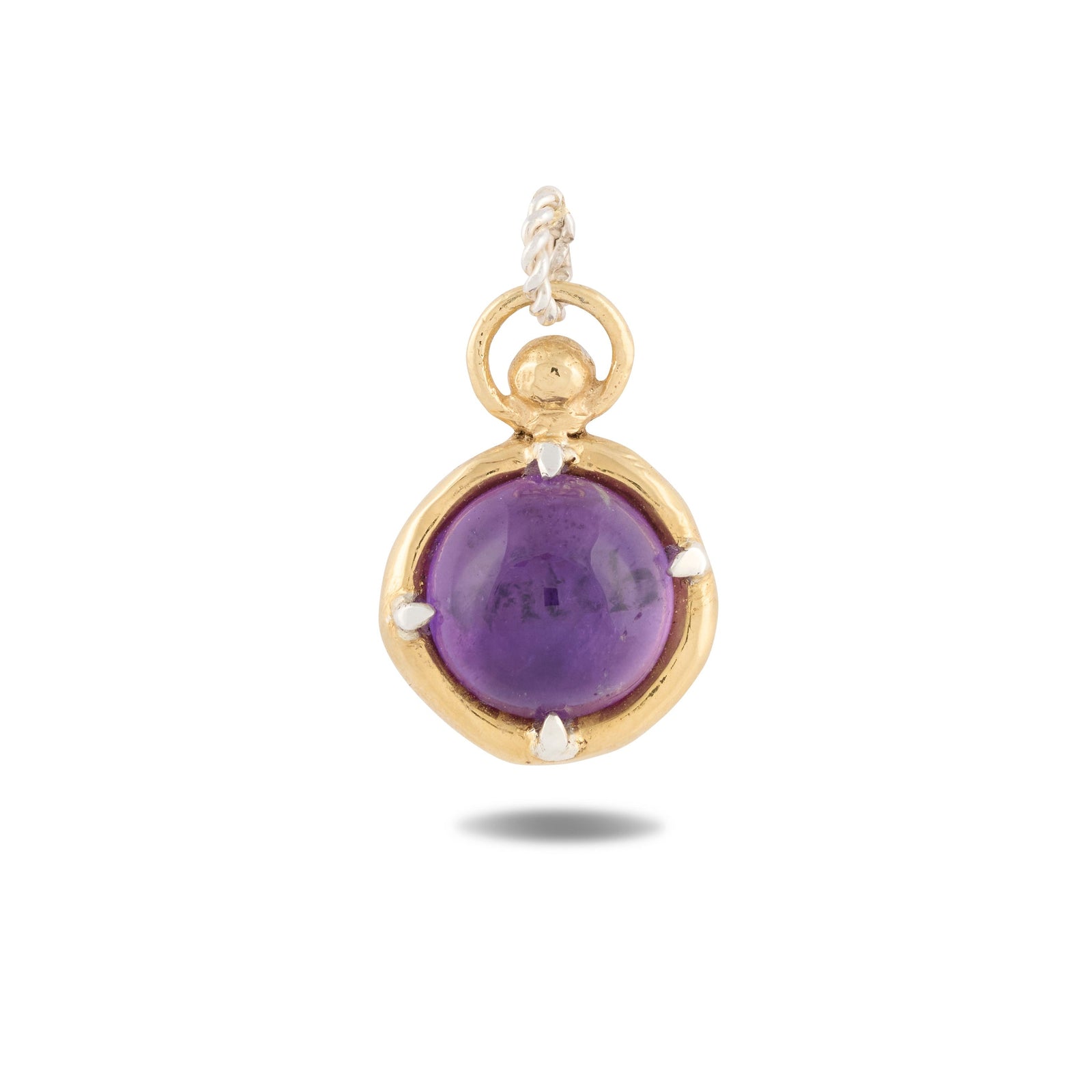 A gold pendant from Jessica de Lotz Jewellery, named “There’s A Little Witch In All Of Us Charm,” showcases a round, polished purple gemstone securely held by four prongs at its center. Inspired by enchanting motifs from *Practical Magic 2*, this charm features a twisted loop for easy attachment to your favorite chain and casts a gentle shadow on a white background. It’s an elegant piece that evokes the timeless allure of wax seal charms and vintage chatelaine hand necklace designs.