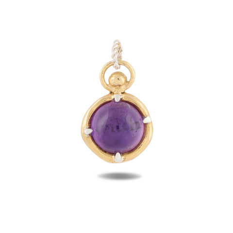 A gold pendant from Jessica de Lotz Jewellery, named “There’s A Little Witch In All Of Us Charm,” showcases a round, polished purple gemstone securely held by four prongs at its center. Inspired by enchanting motifs from *Practical Magic 2*, this charm features a twisted loop for easy attachment to your favorite chain and casts a gentle shadow on a white background. It’s an elegant piece that evokes the timeless allure of wax seal charms and vintage chatelaine hand necklace designs.