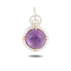 A round purple gemstone pendant titled “There’s A Little Witch In All Of Us Charm” by Jessica de Lotz Jewellery features a smooth, domed cabochon framed in a silver bezel with four gold prongs. Suspended from a twisted silver bail, the pendant echoes the mysterious elegance of Practical Magic 2 and evokes the enchanting allure of wax seal charms, beautifully set against a white background with a soft shadow below.