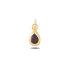 The Our Blood Pendant by Jessica de Lotz Jewellery showcases a teardrop-shaped deep red gemstone at its center, set in gold and evoking the enchanting allure of Practical Magic charms. Suspended from a twisted white cord by a delicate gold loop, the piece stands out against a plain white background, highlighting its unique design and the timeless elegance characteristic of Jessica de Lotz Jewellery.