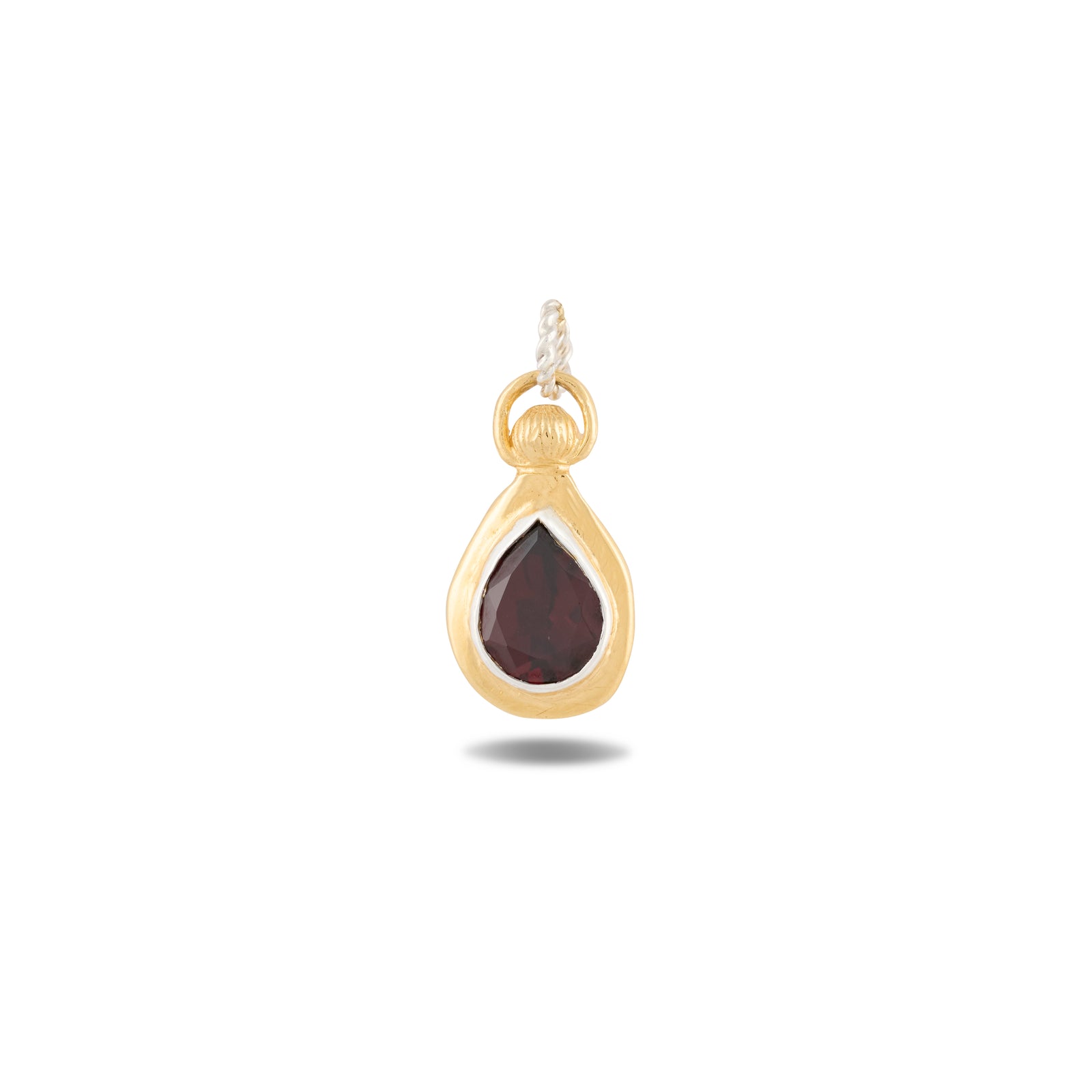 The Our Blood Pendant by Jessica de Lotz Jewellery showcases a teardrop-shaped deep red gemstone at its center, set in gold and evoking the enchanting allure of Practical Magic charms. Suspended from a twisted white cord by a delicate gold loop, the piece stands out against a plain white background, highlighting its unique design and the timeless elegance characteristic of Jessica de Lotz Jewellery.