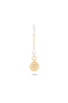 A Verbena Botanical Apothecary Bottle Charm by Jessica de Lotz Jewellery, featuring a gold and white design with a decorative crest reminiscent of sisterhood jewelry, hangs from a chain with alternating white and gold links. The charm is displayed on a plain white background with a subtle shadow beneath it.