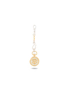 The Verbena Botanical Apothecary Bottle Charm by Jessica de Lotz Jewellery features a circular gold pendant adorned with an ornate, botanical wax-seal-inspired design. Suspended from a silver keychain with a clip at the top, this elegant charm is displayed against a plain white background, casting a faint shadow below.