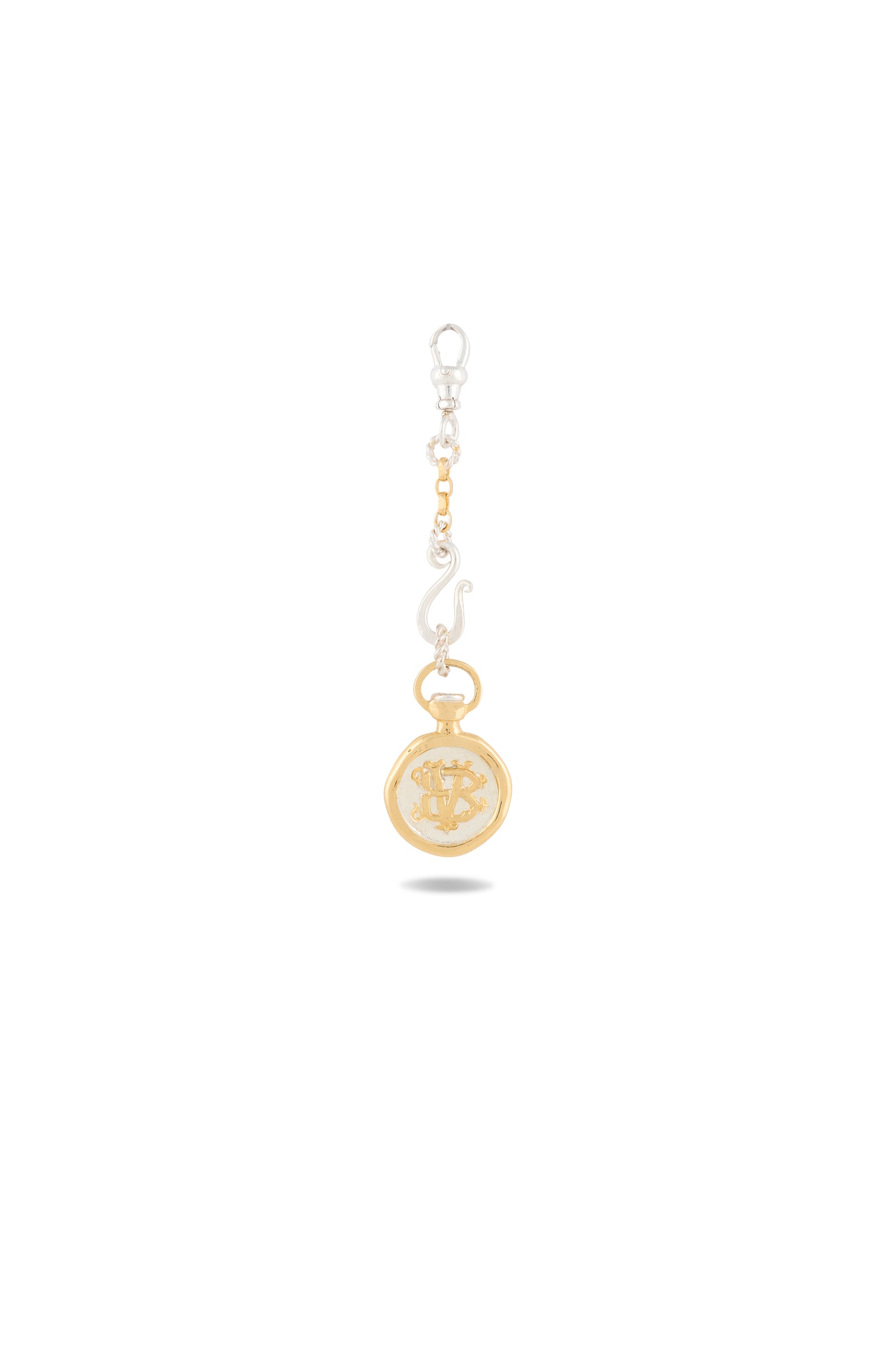The Verbena Botanical Apothecary Bottle Charm by Jessica de Lotz Jewellery features a circular gold pendant adorned with an ornate, botanical wax-seal-inspired design. Suspended from a silver keychain with a clip at the top, this elegant charm is displayed against a plain white background, casting a faint shadow below.