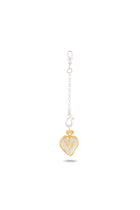 A small gold and silver heart-shaped Amas Veritas Spell Charm by Jessica de Lotz Jewellery hangs from a short silver chain with a clasp, reminiscent of modern chatelaine accessories. The center of the heart features a raised gold letter V, evoking the spirit of sisterhood charms found in Practical Magic 2. The charm casts a faint shadow on the white background.
