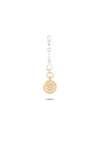 A gold and silver keychain charm, the Verbena Botanical Apothecary Bottle Charm by Jessica de Lotz Jewellery, features a round pendant with a gold rim engraved with a stylized crown and shield. Reminiscent of sisterhood jewelry, it is finished with a decorative silver clasp and small silver accents above the pendant, all set against a white background.