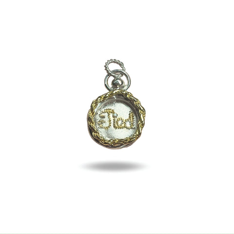 The Tied Charm by Jessica de Lotz Jewellery is a round silver pendant with a gold braided border and “God” in cursive, resembling a wax seal. It features a silver loop for attaching to a chain and is shown on a white background.